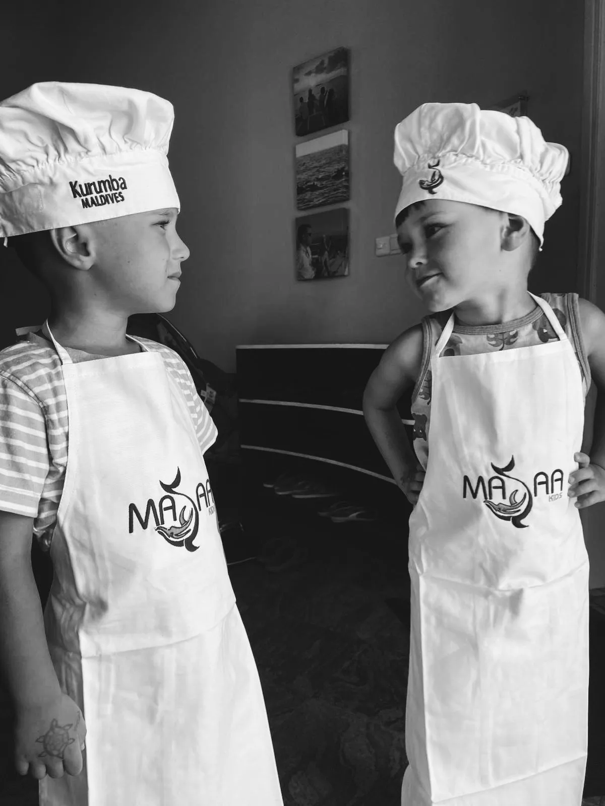 Two children dressed as little chefs in aprons and chef hats
